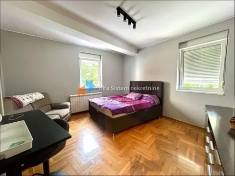 Furnished bedroom with a double bed, desk, and a two-seater sofa. - image 10