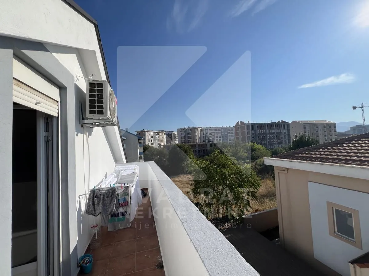 Long balcony with a view of surrounding buildings and greenery.