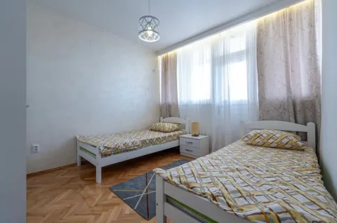 Bedroom with two single beds, a nightstand, and a large window. - image 14