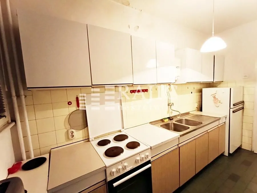 Smaller kitchen with white cabinets, stove, and sink.