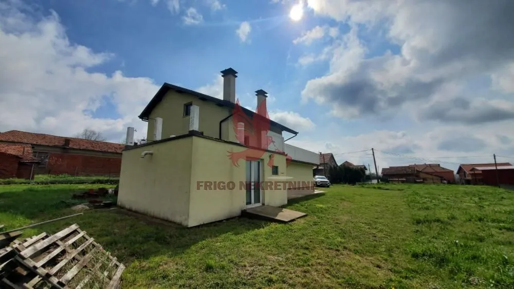 Pogled na zadnju stranu kuće sa velikim dvorištem.