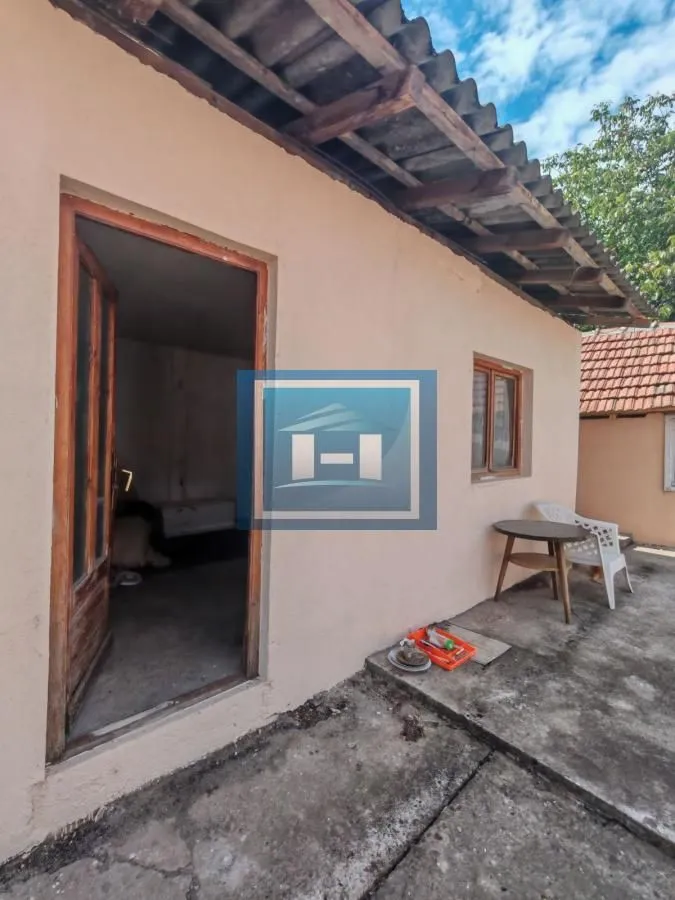 Pogled na spoljašnjost kuće sa ulaznim vratima i malim dvorištem.