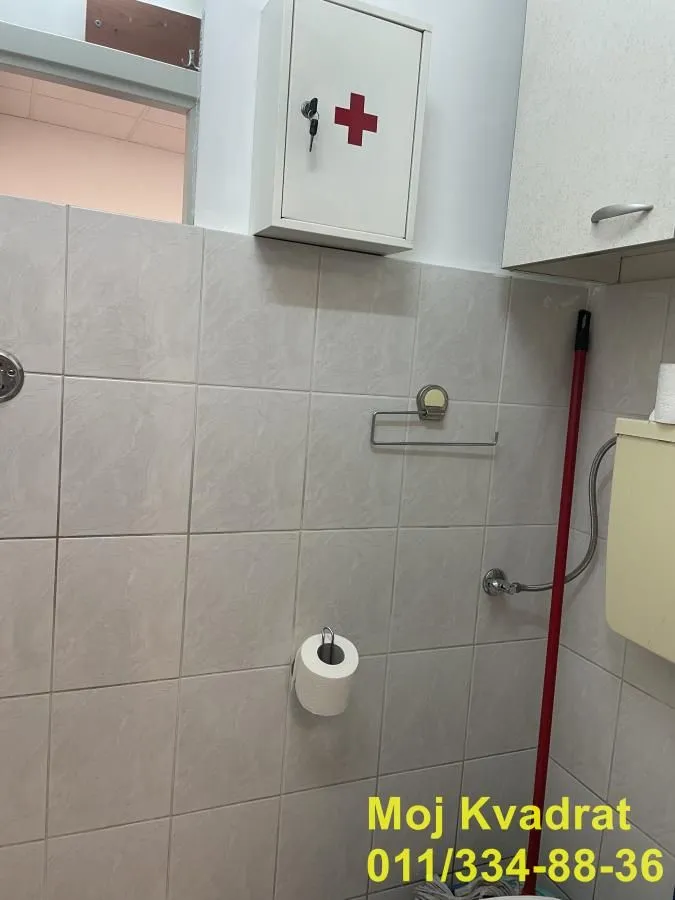 View of the tiled part of the bathroom with sanitary facilities and a cabinet.
