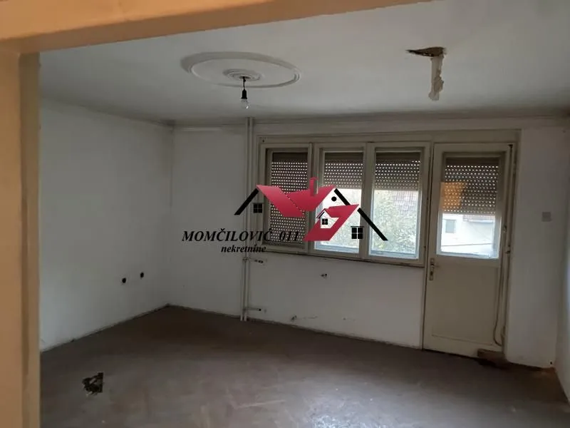 Prazna prostorija sa prozorom i vratima koja vode na terasu.