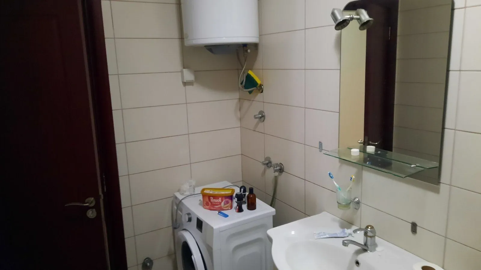 Jednostavno kupatilo sa veš mašinom, bojlerom i lavaboom.