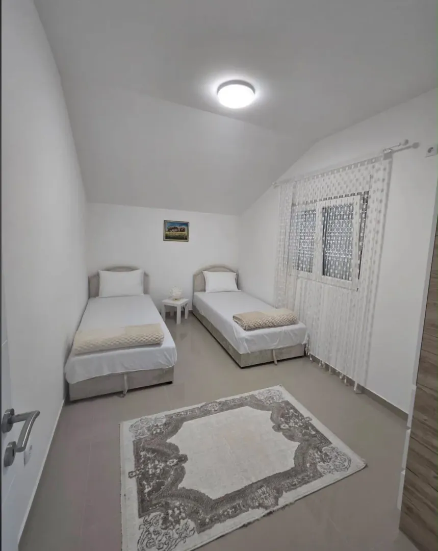 Bright bedroom with two single beds, a rug, and a window.