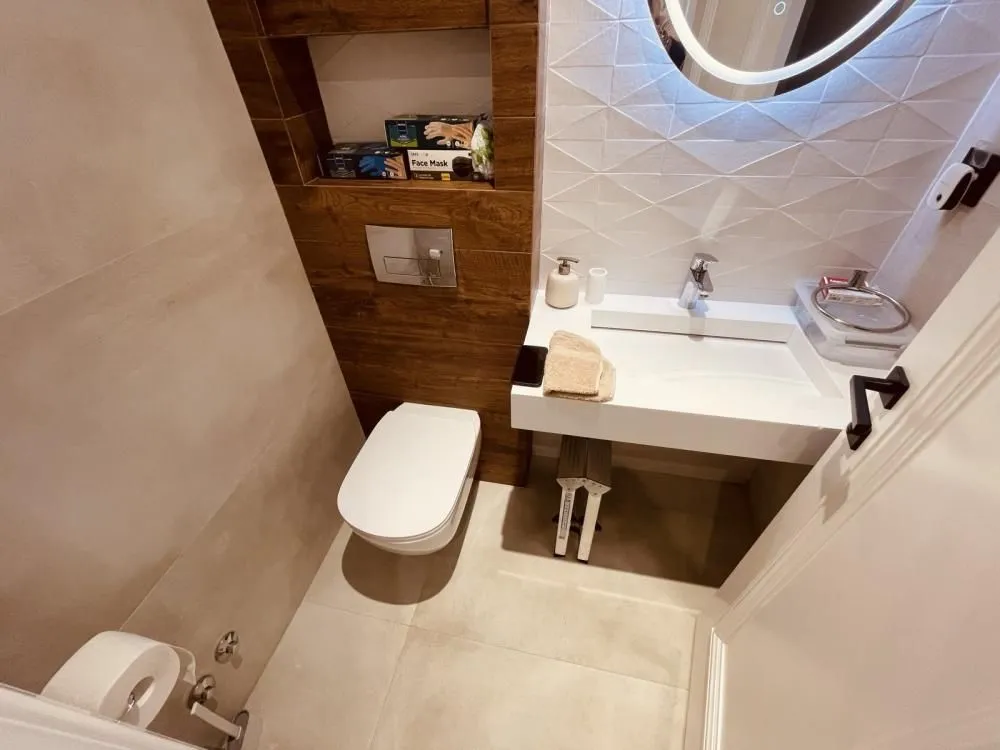Manje kupatilo sa WC šoljom, umivaonikom i ogledalom.