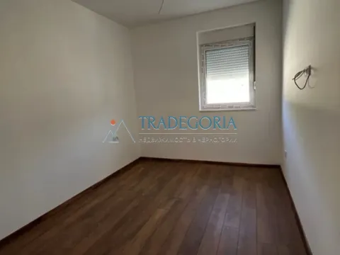 Prazna soba sa bijelim zidovima, drvenim podom i prozorom. - image 4