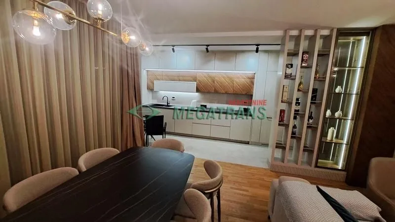 Dnevni boravak sa trpezarijom i modernom kuhinjom u pozadini.