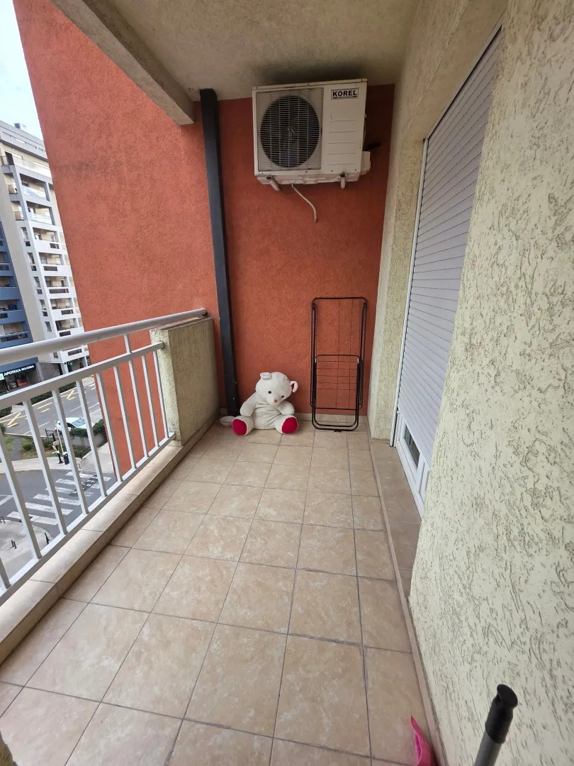 Small tiled balcony with an air conditioning unit and a drying rack.