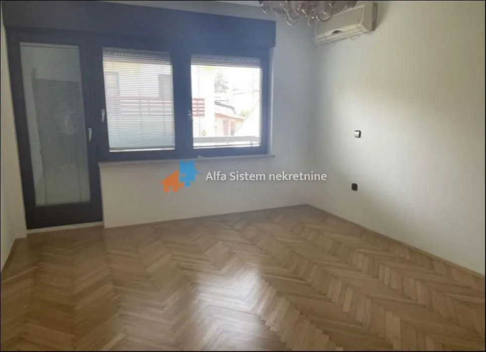 Empty room with hardwood flooring and windows.
