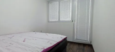 A simple bedroom with a double bed and windows with blinds. - image 15
