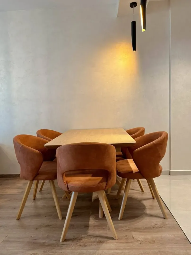 Dining area with a wooden table and modern orange chairs.