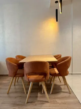 Dining area with a wooden table and modern orange chairs. - image 4