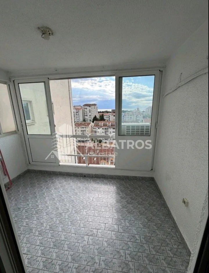 Enclosed balcony with tiled flooring and city views.