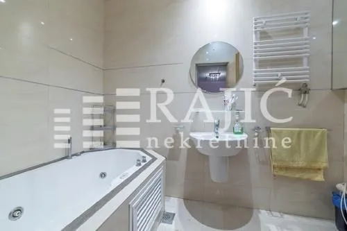 Modern bathroom with a bathtub, washbasin, and tiled walls.