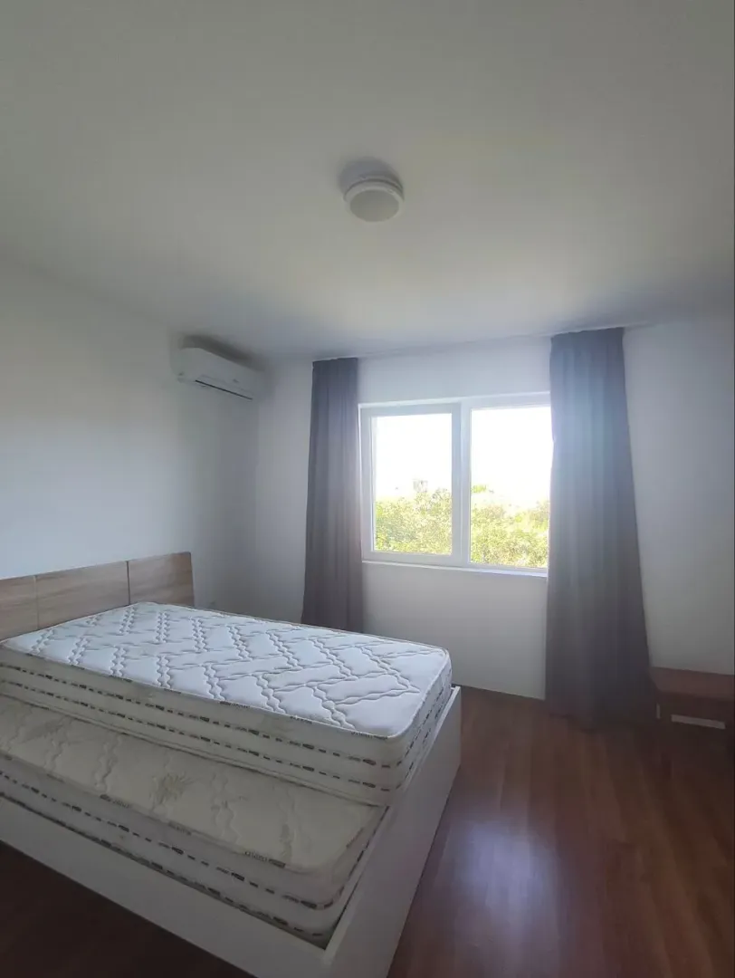 Spavaća soba sa bračnim krevetom, klima-uređajem i prozorom sa tamnim zavjesama.