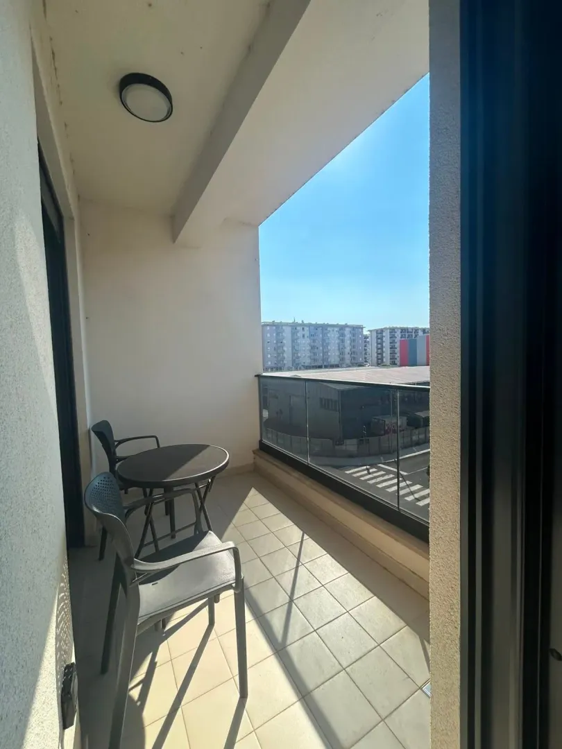 Covered balcony with patio furniture and a city view.