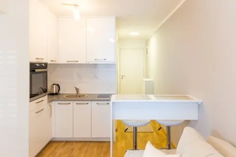Small white kitchen with a breakfast bar and bar stools. - image 4