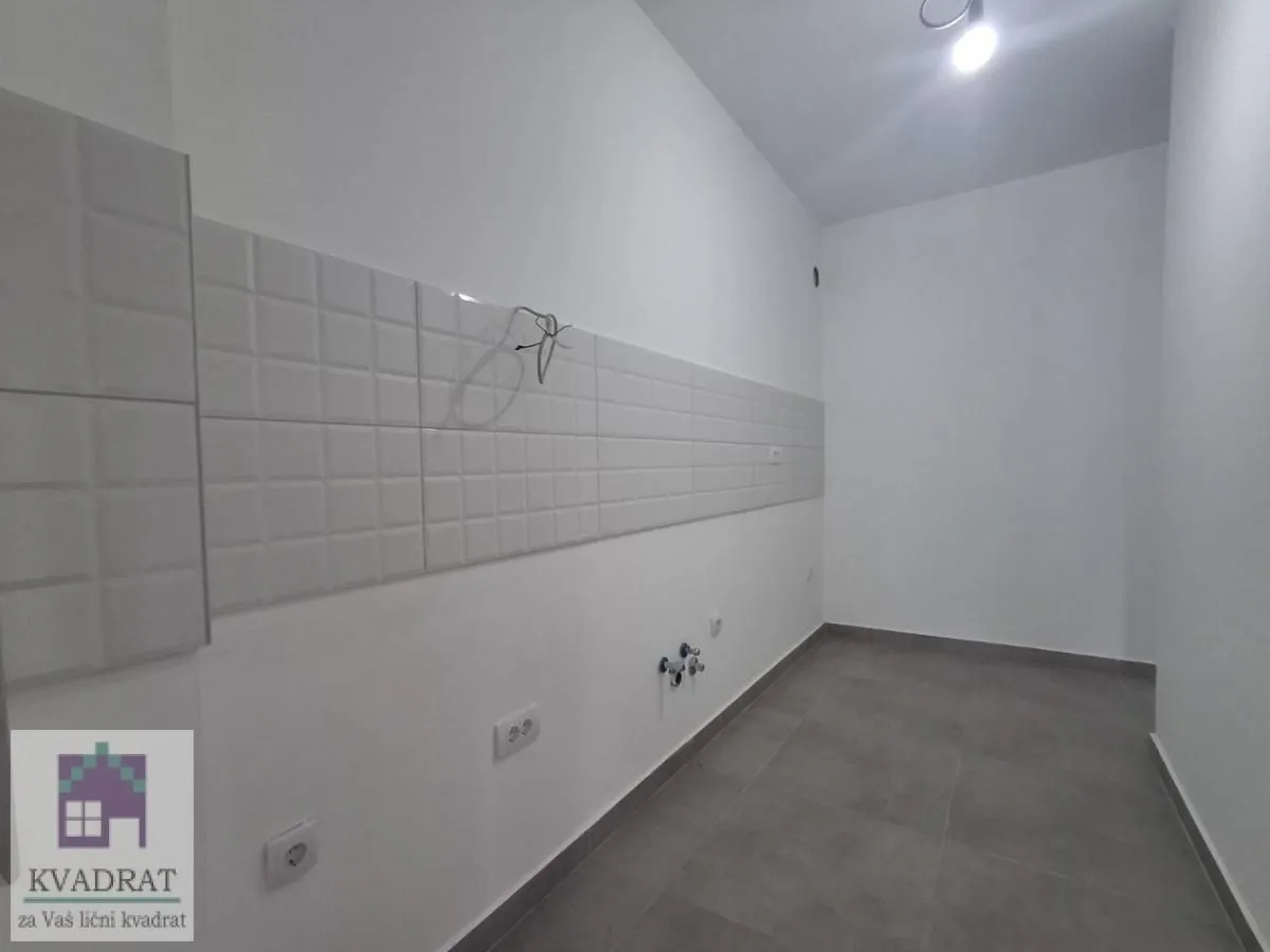 Prazna prostorija pripremljena za ugradnju kuhinje sa pločicama i priključcima.