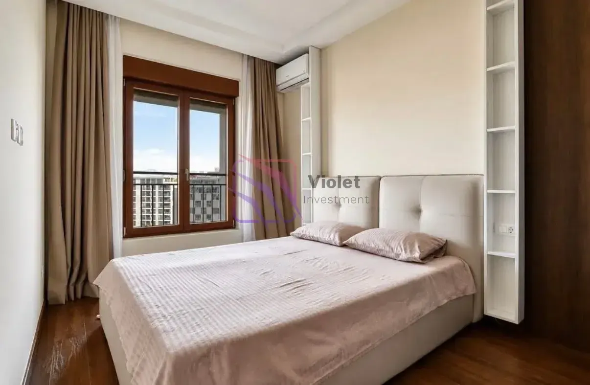 Furnished bedroom with a double bed, window, and built-in shelving.