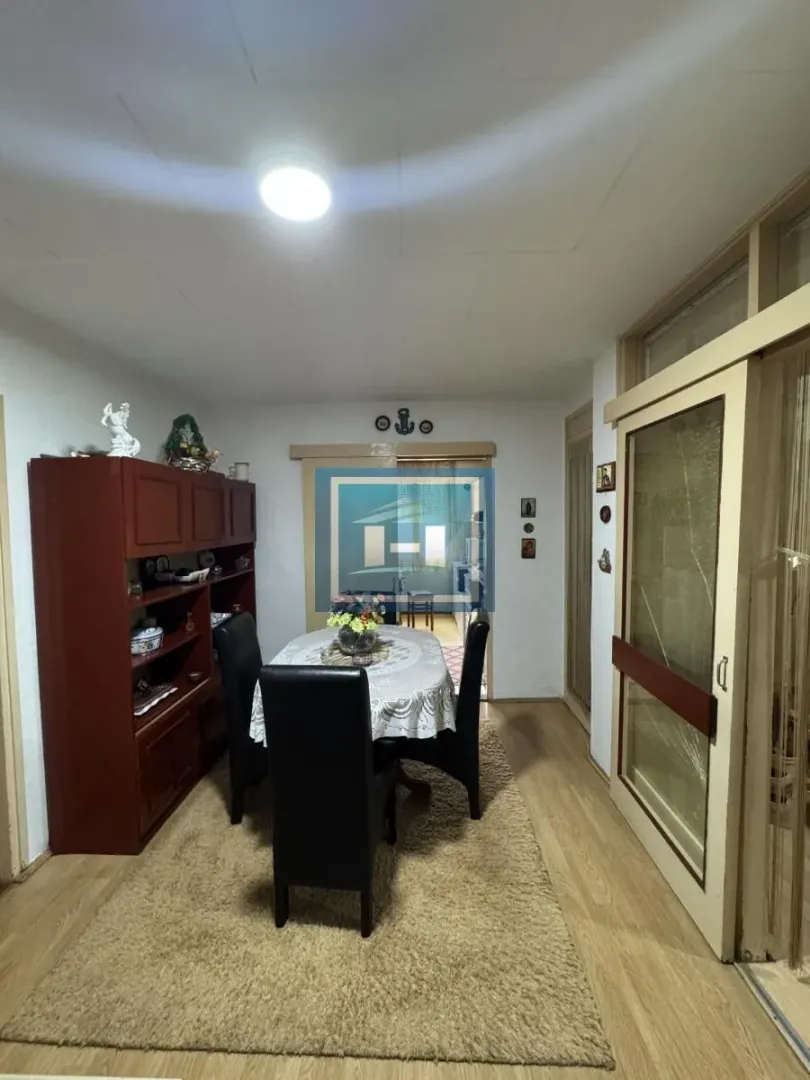 Trpezarija sa stolom, stolicama i drvenom komodom.