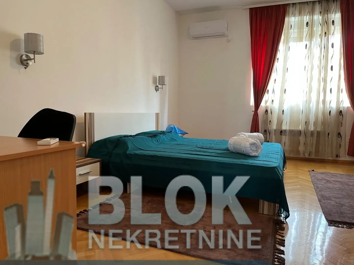 Spavaća soba sa bračnim krevetom, radnim stolom i klimom.