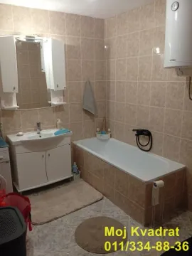 Bathroom equipped with a bathtub, vanity unit with sink, and water heater. - image 6