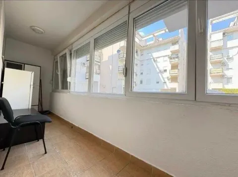 Enclosed balcony with a view of surrounding buildings. - image 6