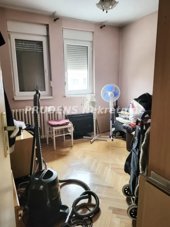 Small room with two windows, parquet flooring and various household appliances.
