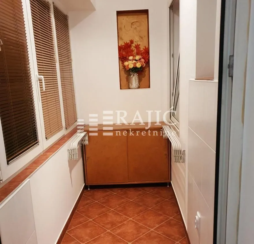Enclosed balcony with a cabinet and a decorative wall niche.