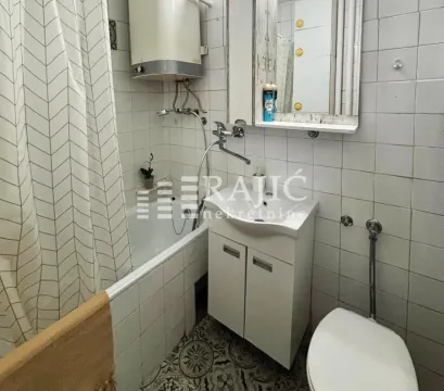 Smaller bathroom with a bathtub, washbasin, and toilet. - image 12