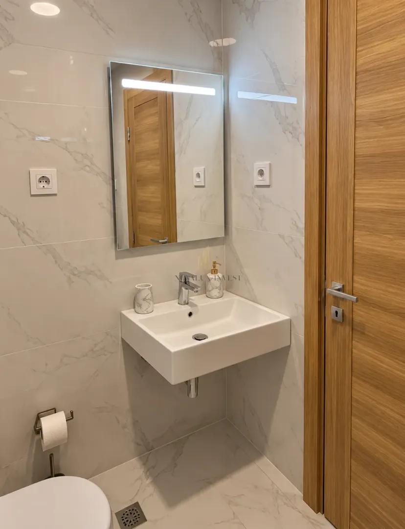 Modern bathroom equipped with a washbasin, mirror, and marble tiles.