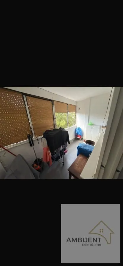 Zastakljeni balkon sa roletnama i stalkom za sušenje veša.