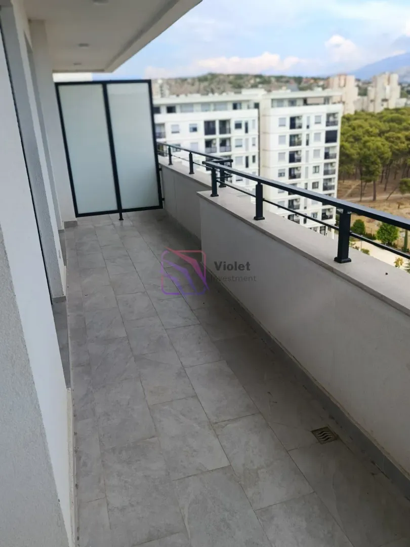 Prostrani popločani balkon sa metalnom ogradom i pogledom na grad.