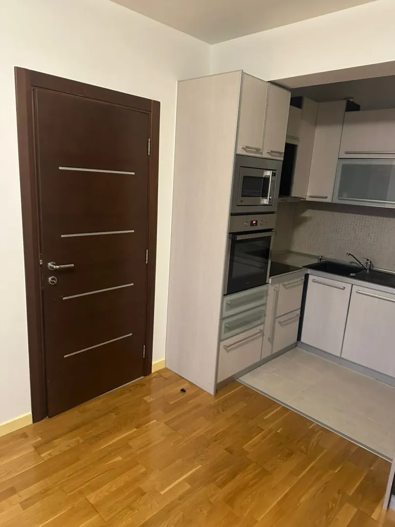 Bright kitchen with built-in appliances next to a wooden door.