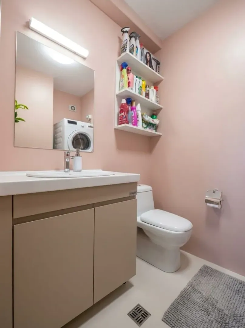 Compact bathroom with a sink, toilet, washing machine, and storage shelves.