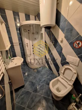 Small bathroom with a shower cabin, washbasin, and toilet. - image 4