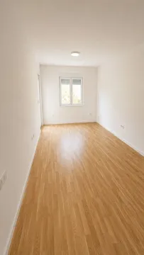 Prazna soba sa svijetlim drvenim podom i prozorom. - image 5