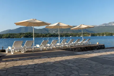 Ležaljke i suncobrani na betonskoj plaži pored mora sa pogledom na planine. - image 4
