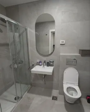 Moderne kupatilo sa tuš kabinom, umivaonikom i toaletom u sivim tonovima pločica. - image 5