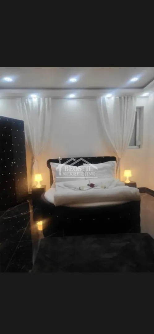 Bedroom with a large round bed and bedside lamps.