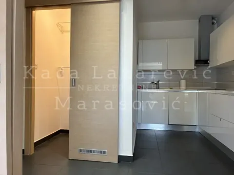 White kitchen and the entrance to a small storage room with a sliding door. - image 7