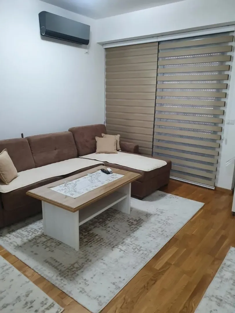 Comfortable living room with a corner sofa, coffee table, and windows with blinds.