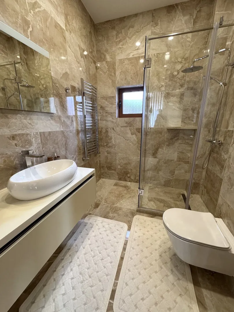 Modern marble-tiled bathroom featuring a walk-in shower and a vessel sink.