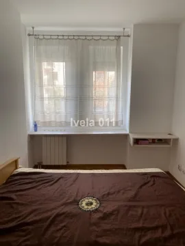Spavaća soba sa bračnim krevetom i prozorom sa zavesama. - image 3