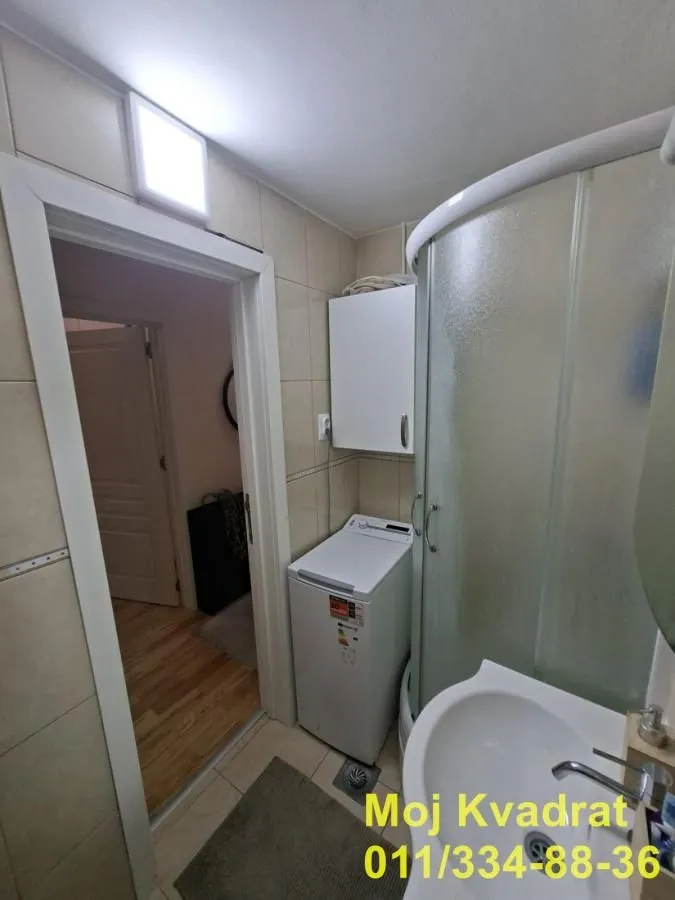 Kupatilo sa tuš kabinom, umivaonikom i mašinom za veš.