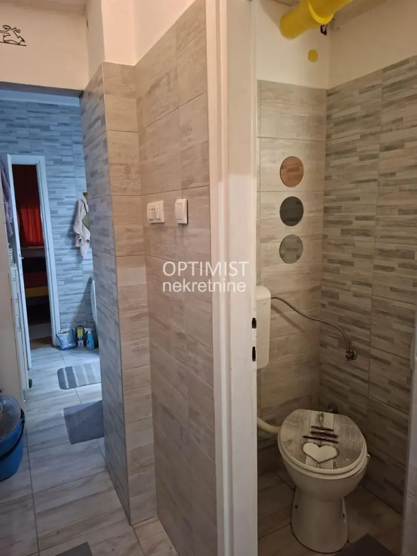 View of the bathroom with ceramic tiles and toilet.