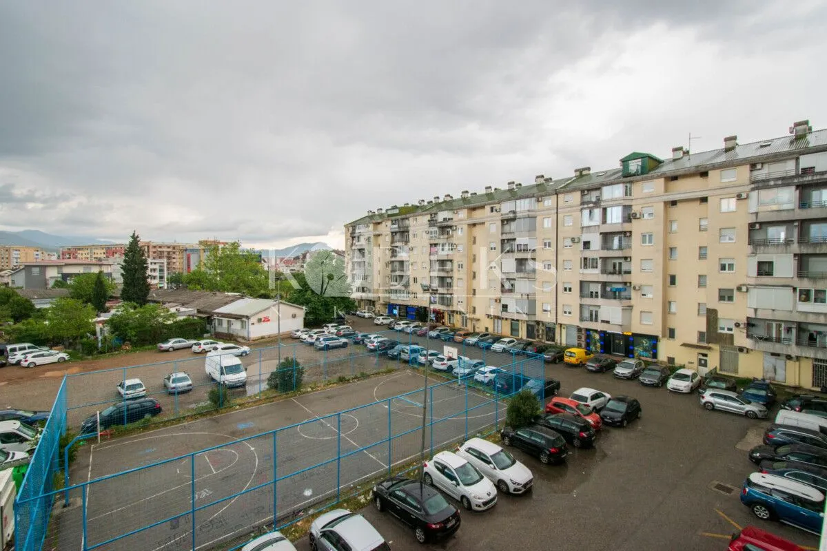 View from the window overlooking surrounding residential buildings, a parking lot, and a sports court.