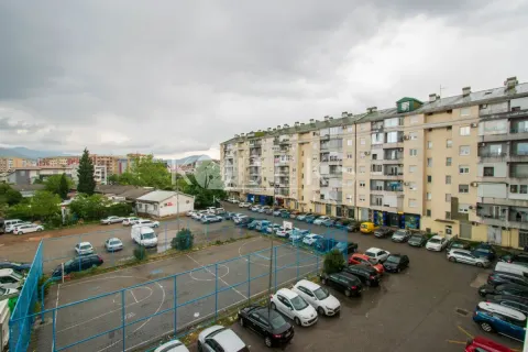 View from the window overlooking surrounding residential buildings, a parking lot, and a sports court. - image 8